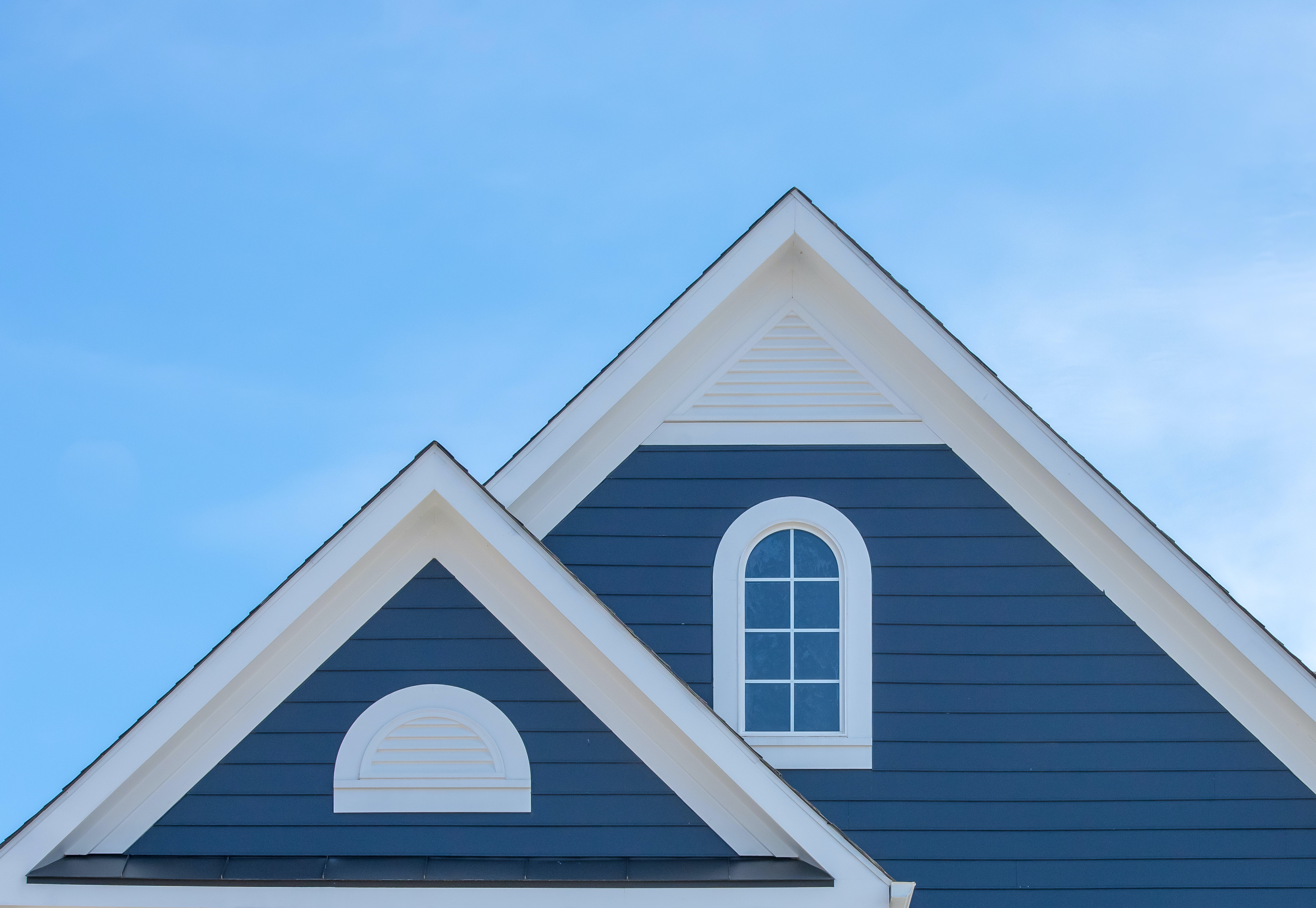 White attic window vent on blue siding, gable, corbel, louver on a new construction luxury